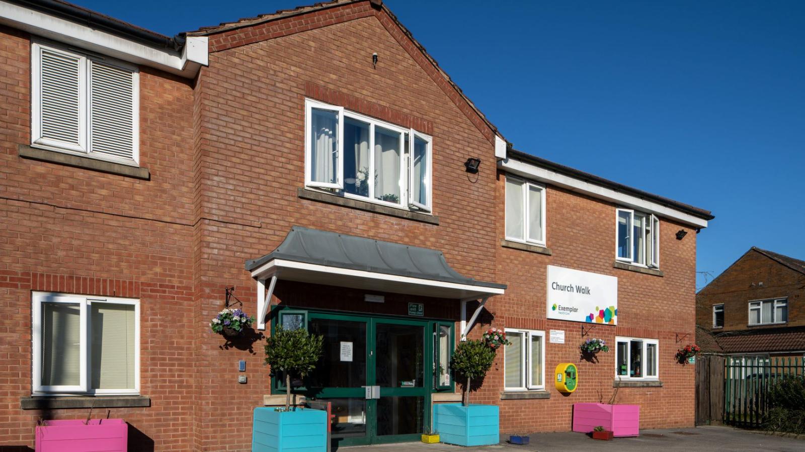 Outside of a care home with blue and pink planters