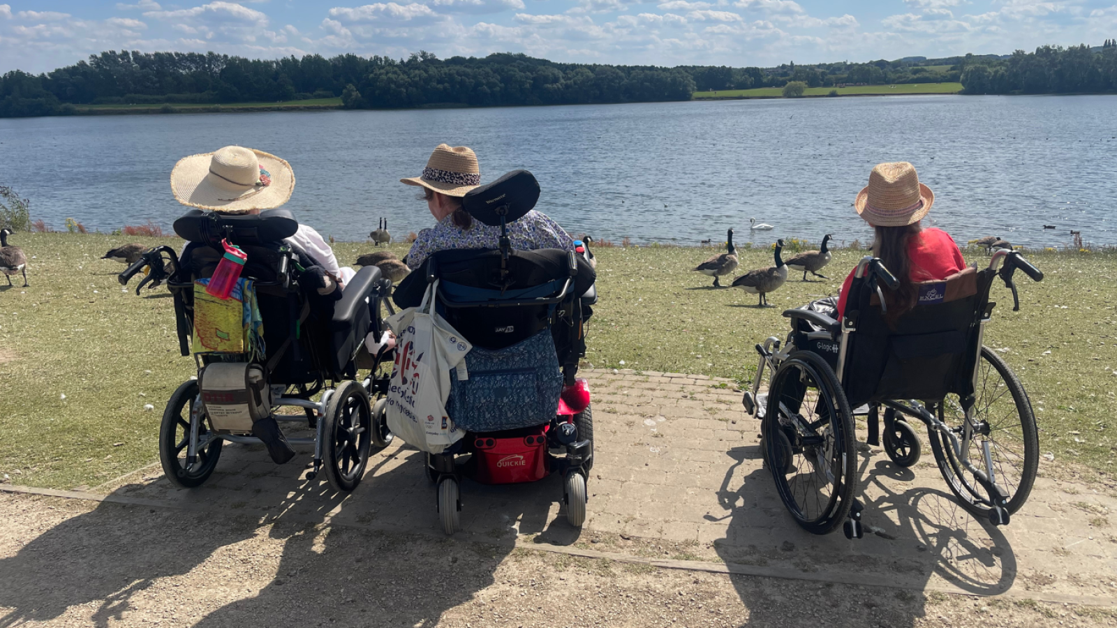 Three people in wheelchairs overlooking a lake