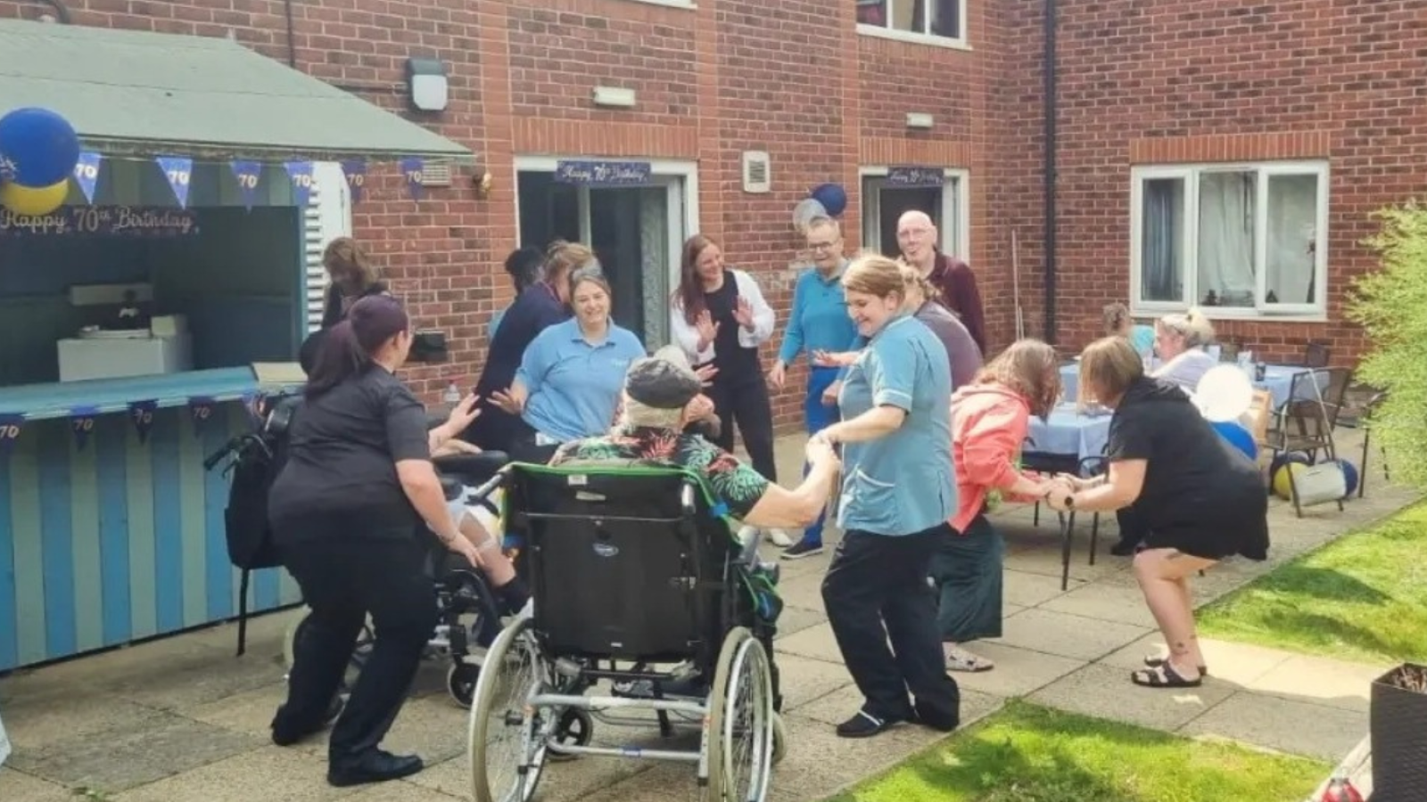 A group of people having a party in the garden, some people are in wheelchairs