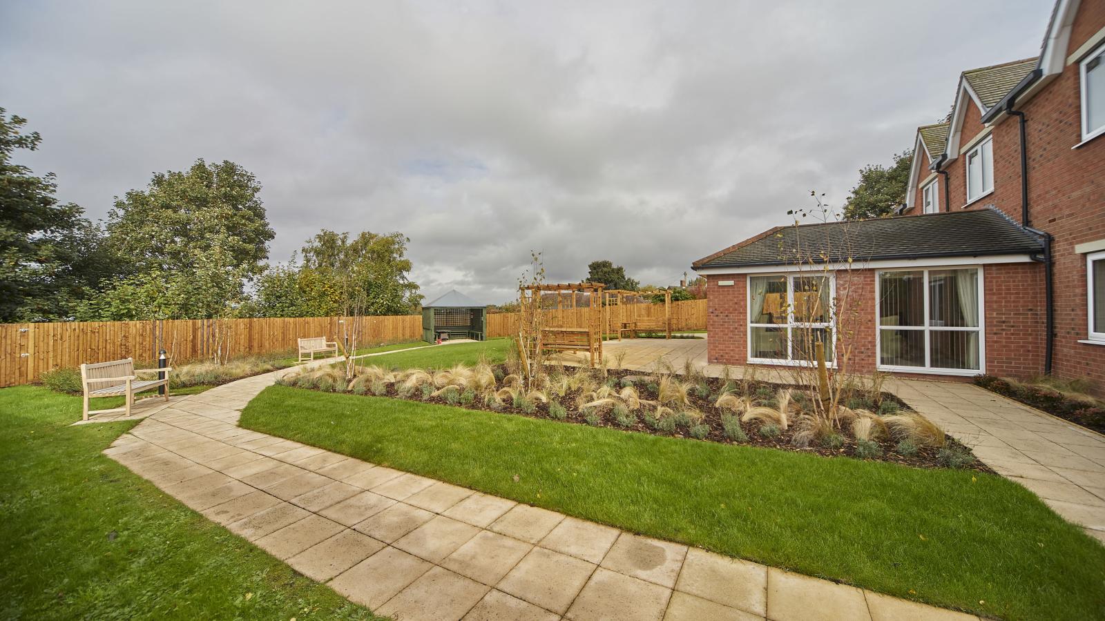Garden of care home with patio, paths and grassed areas