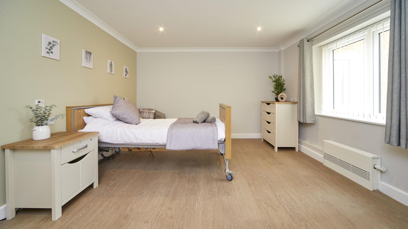 Care home bedroom with a set of drawers and bedside table