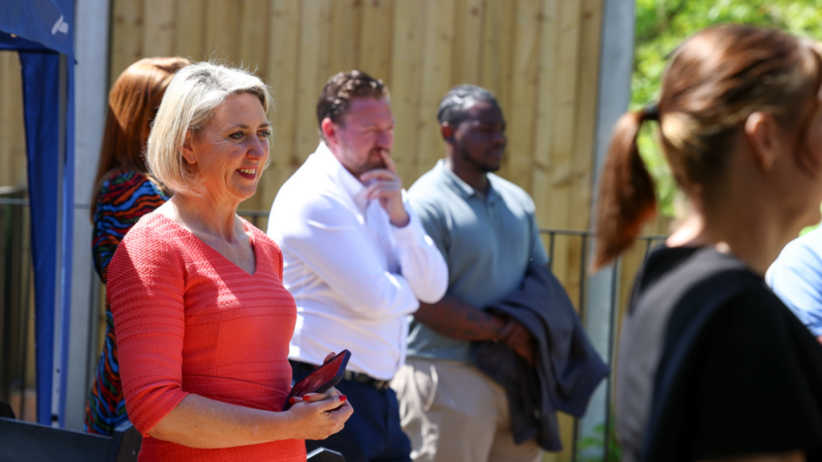 Guests are gathered in a garden listening to speeches