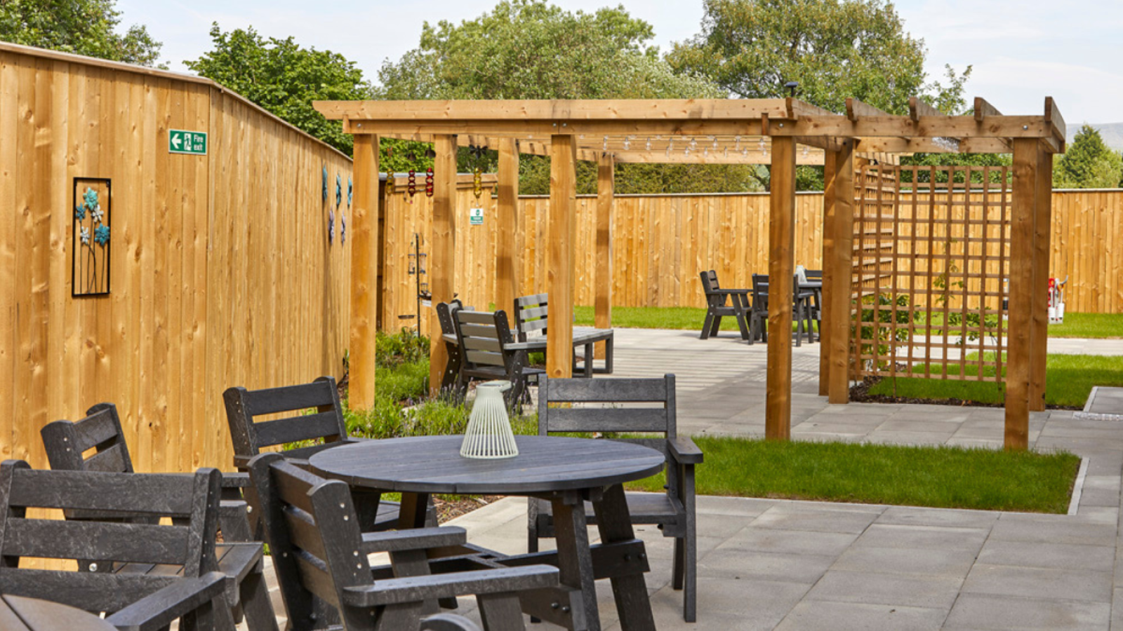 A photo of a garden surrounded by a wooden fence with tables and chairs