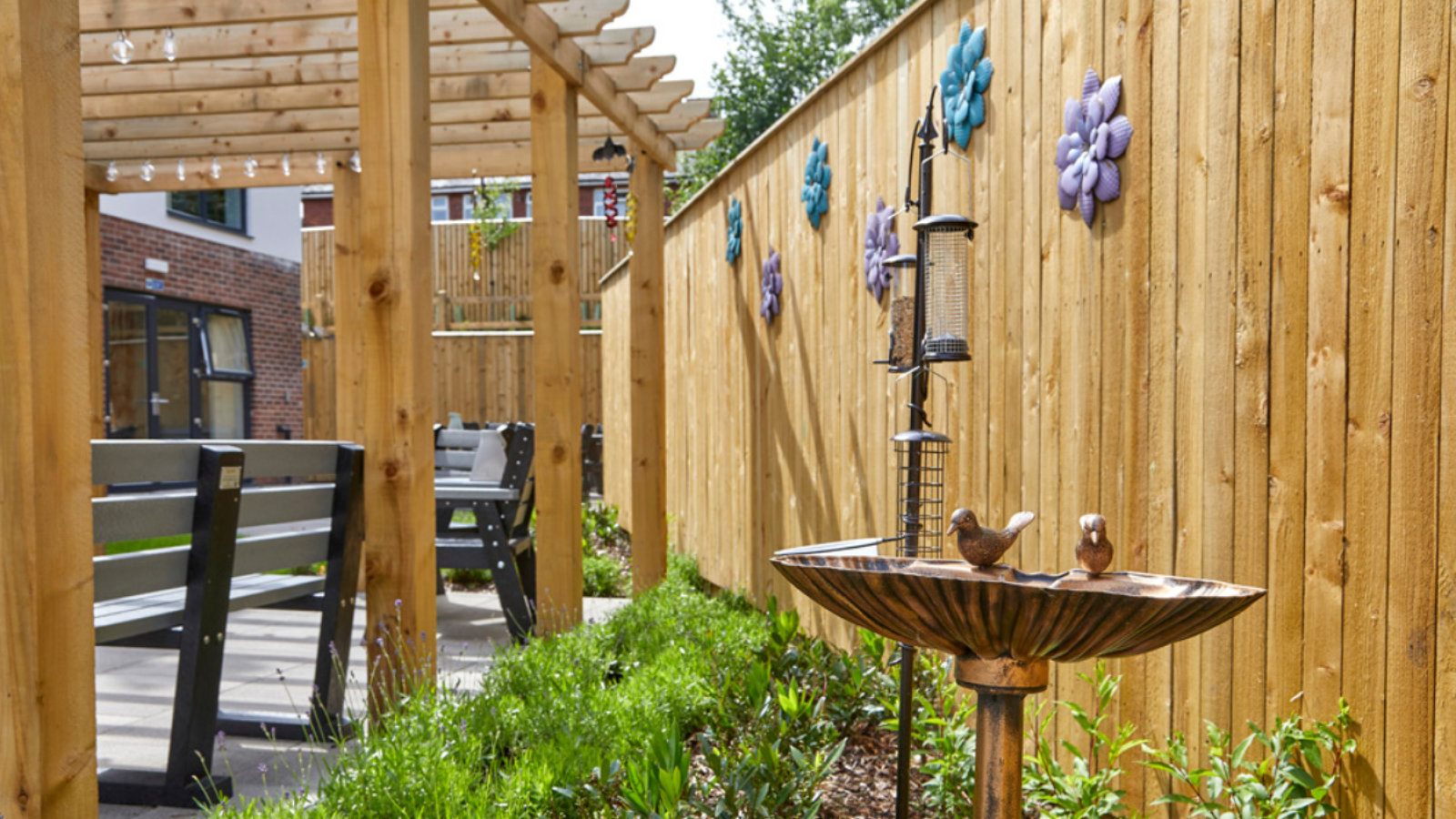 A photo of a garden surrounded by a wooden fence and a water feature