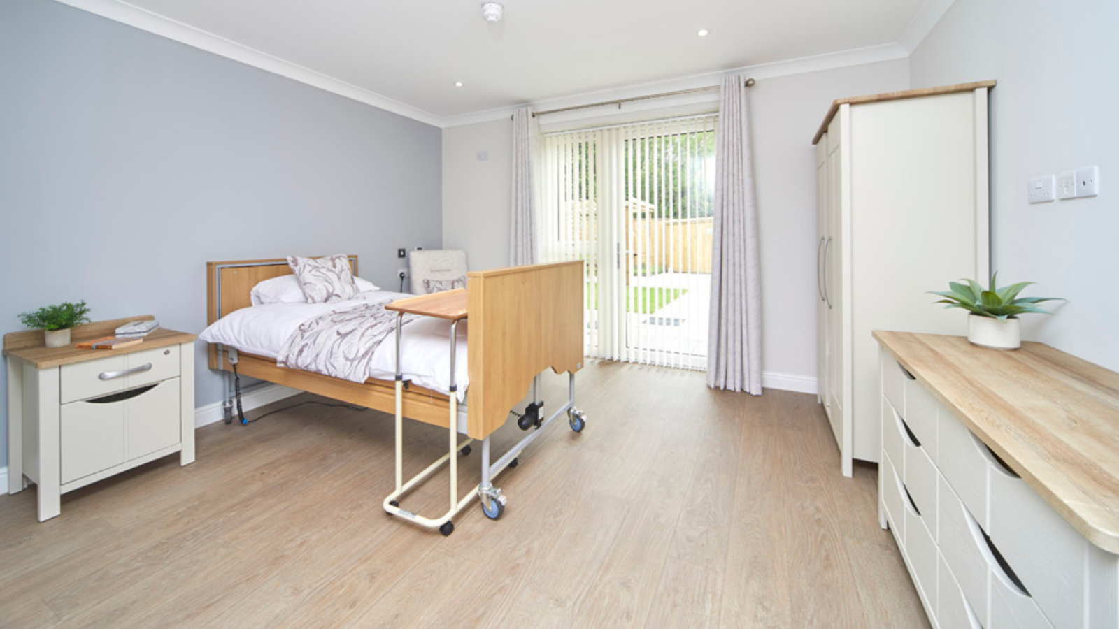 A photo of a bedroom with double doors leading into a garden, with furniture around the room