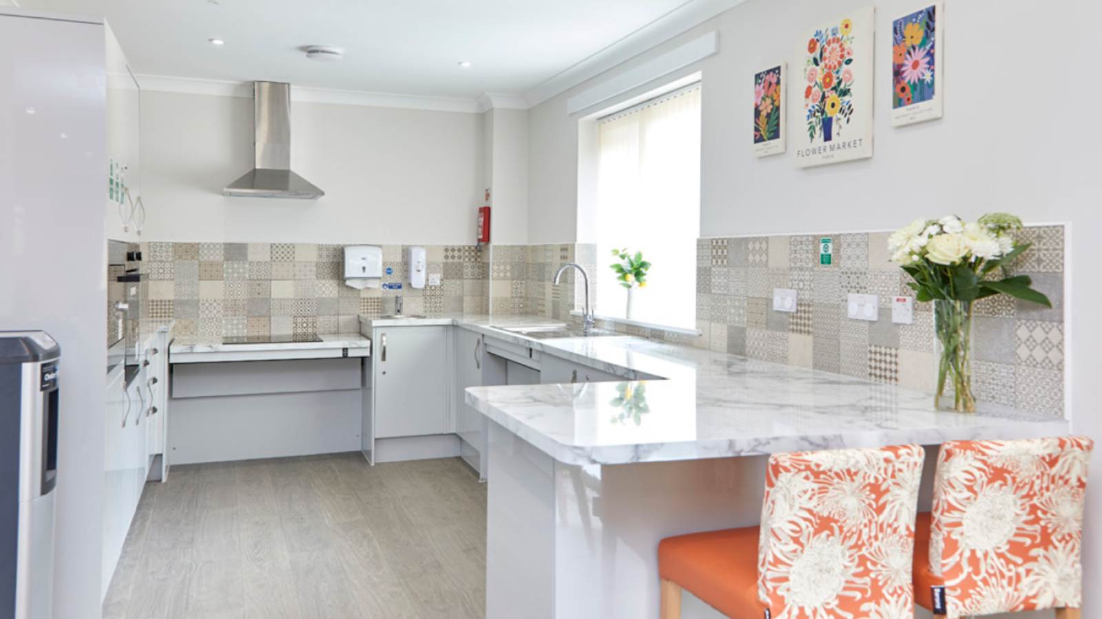 A photo of a kitchen area with a rise and fall hob area, a high stool table and chairs