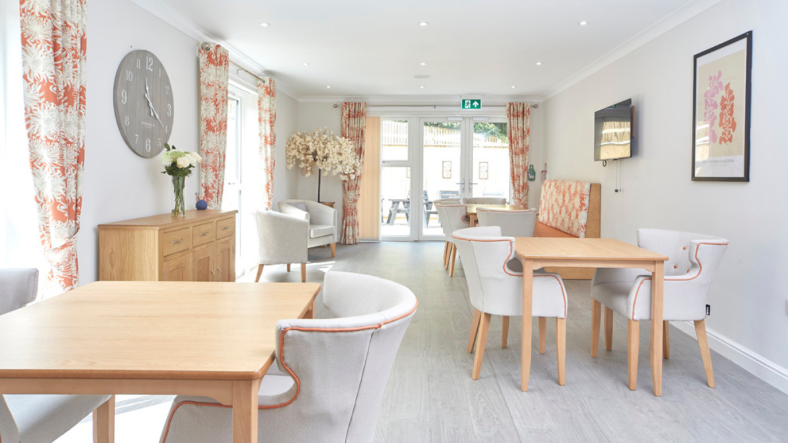 A photo of a large room filled with different style tables and chairs, with double doors leading out into a garden
