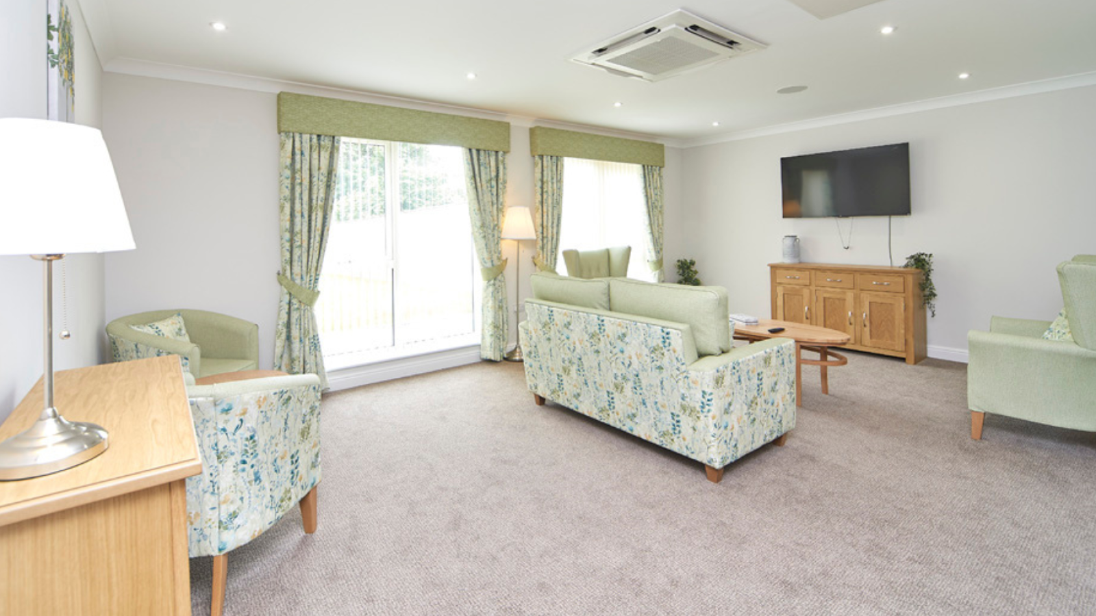 A lounge area with various different styles of seating, facing towards a TV on the wall