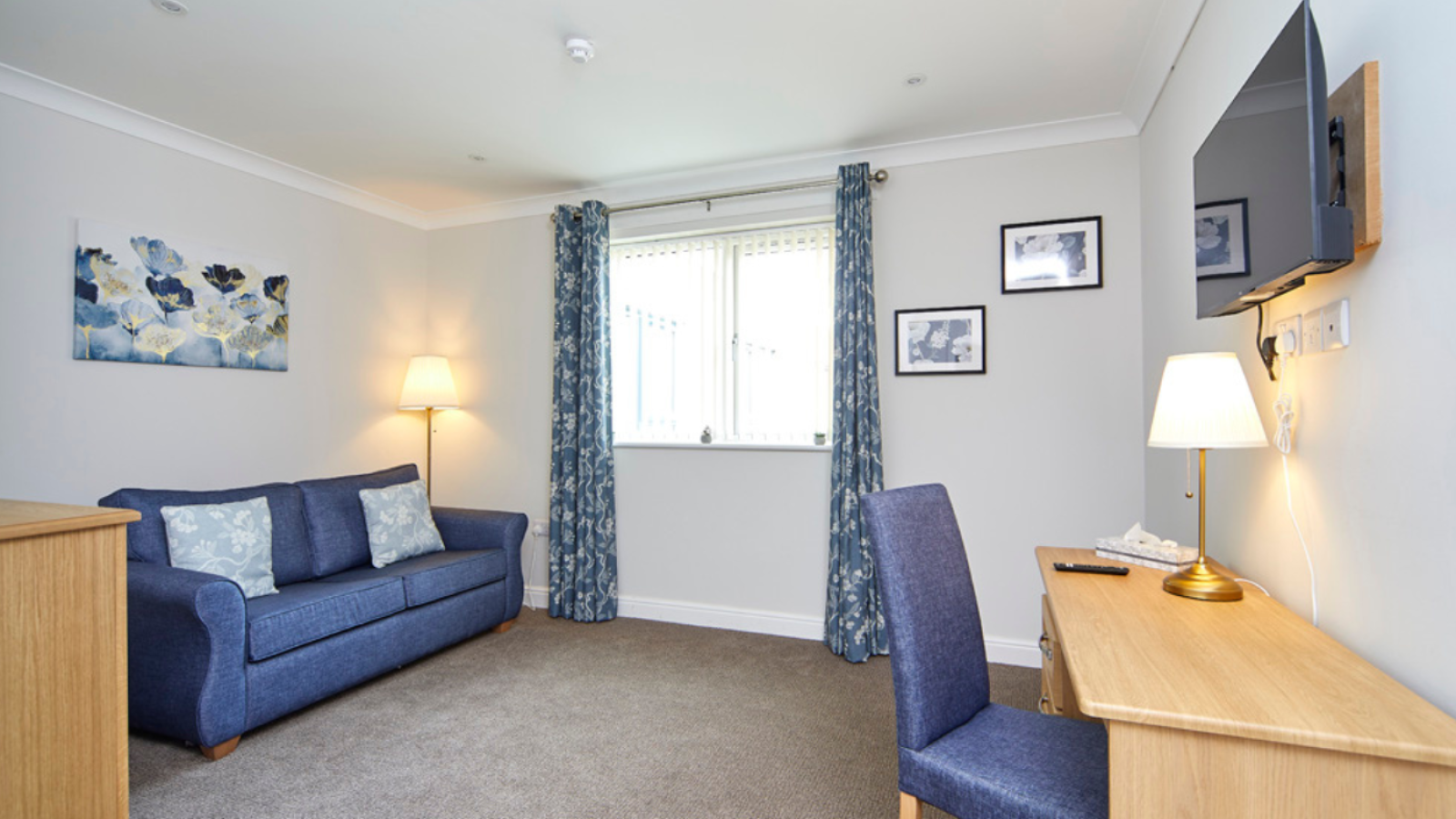 A room with a desk and chair, a large sofa bed and window