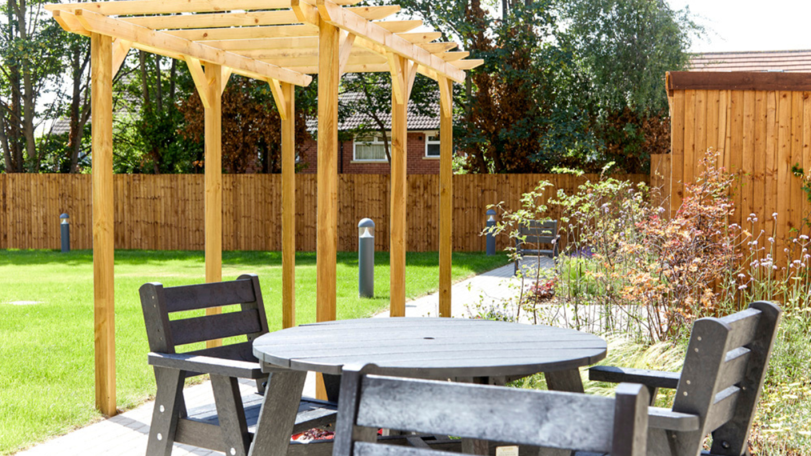 Black garden furniture and a wooden pergola set in a garden