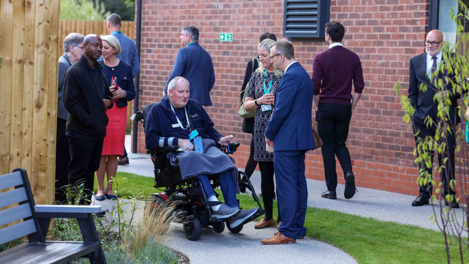 People stood talking in a care home garden with one person in a wheelchair