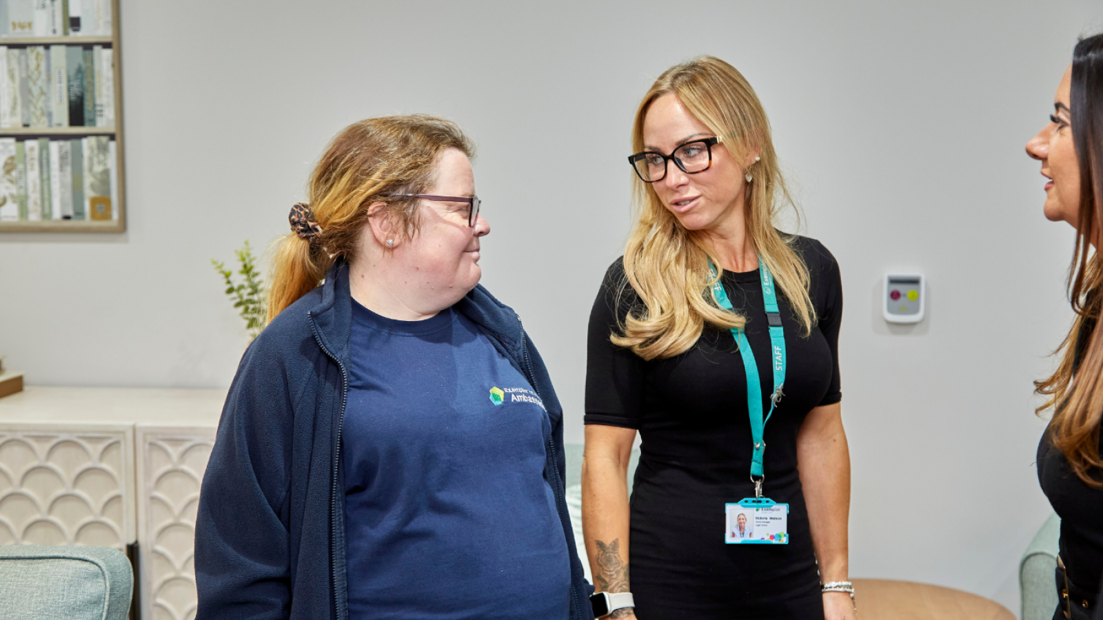 Three people stand talking in a care home
