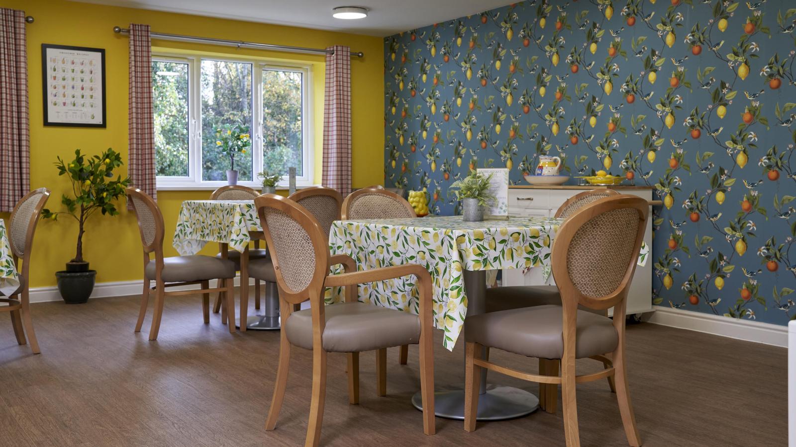 Dining room with two tables set up and bright wallpaper