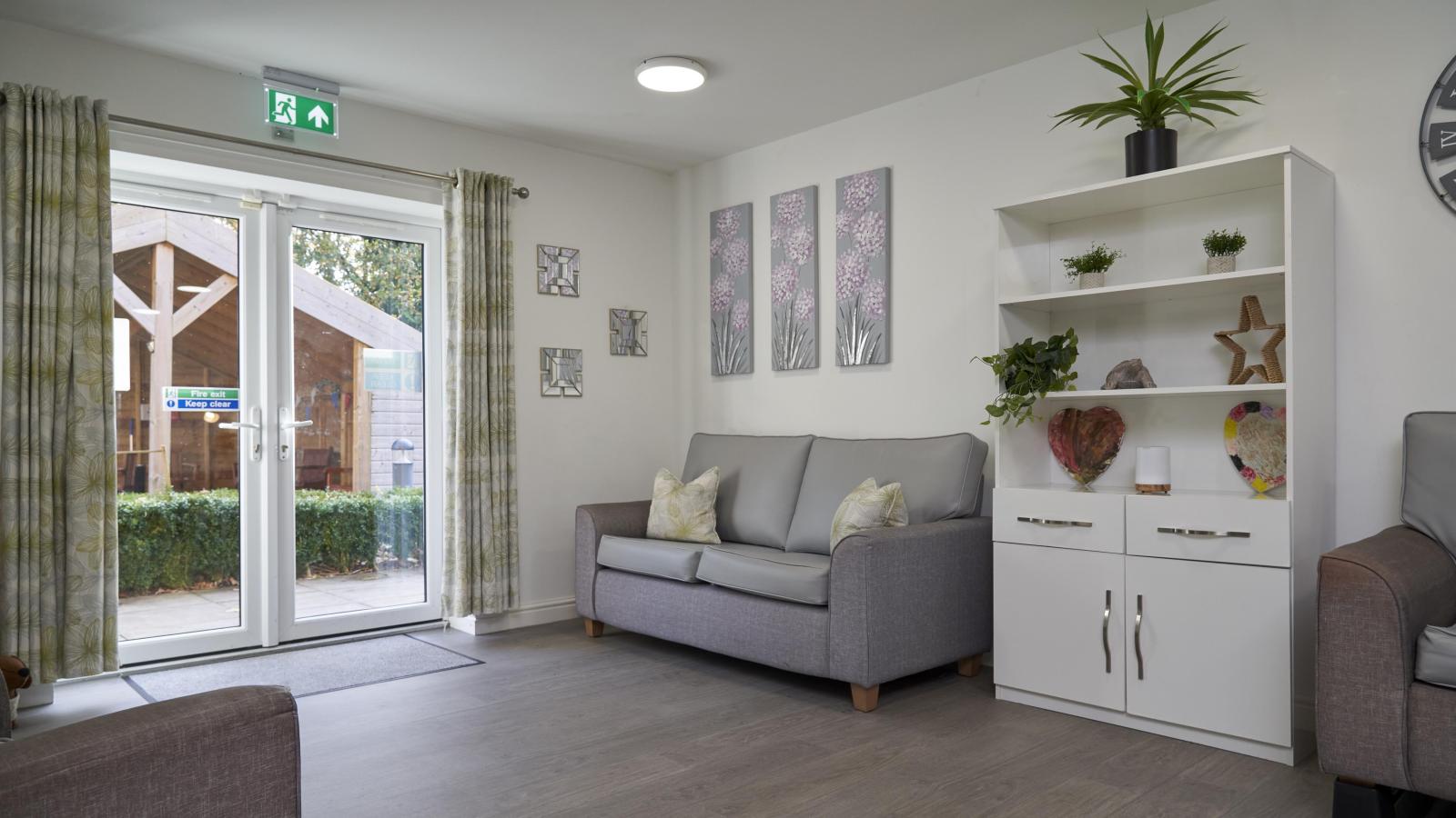 Lounge area with sofa, shelves, and patio doors leading out to garden