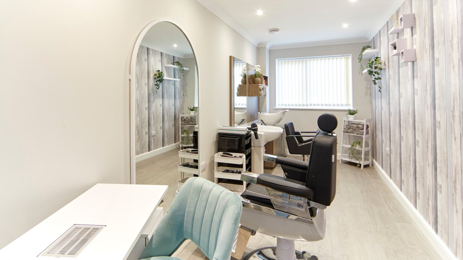 Modern salon with wood-paneled walls, mirrors, and soft lighting. Features barber chairs, a styling station, and decorative plants, creating a calm atmosphere.