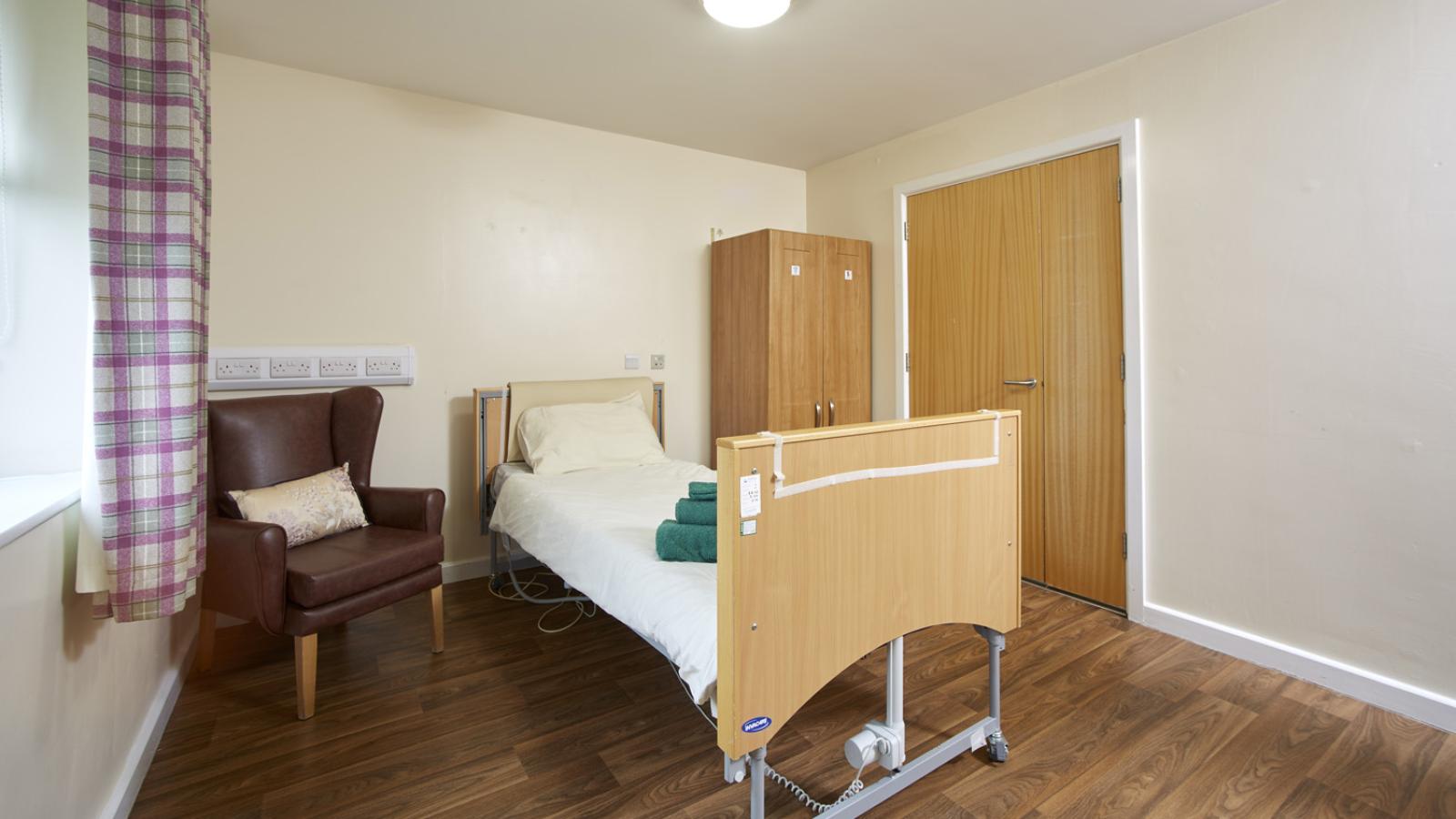 Bedroom set up with single bed, wardrobe, and chair