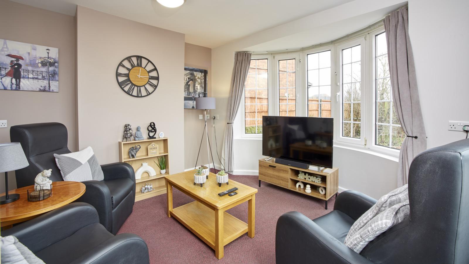 Lounge in a house with two chairs, coffee table, and TV