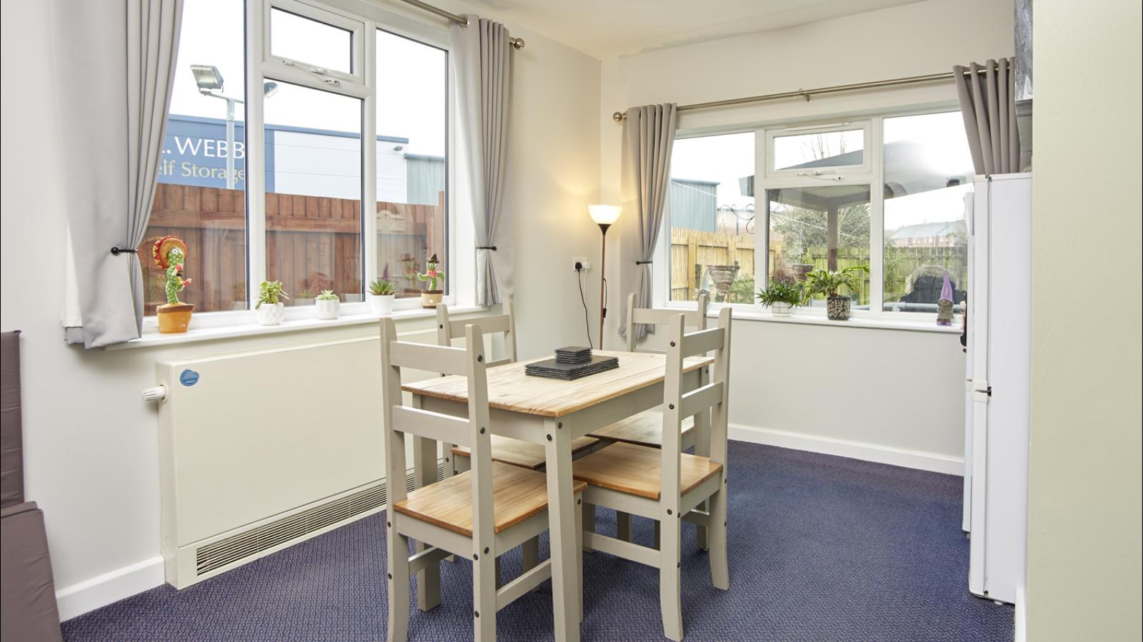 Dining room with table and four chairs, with two windows