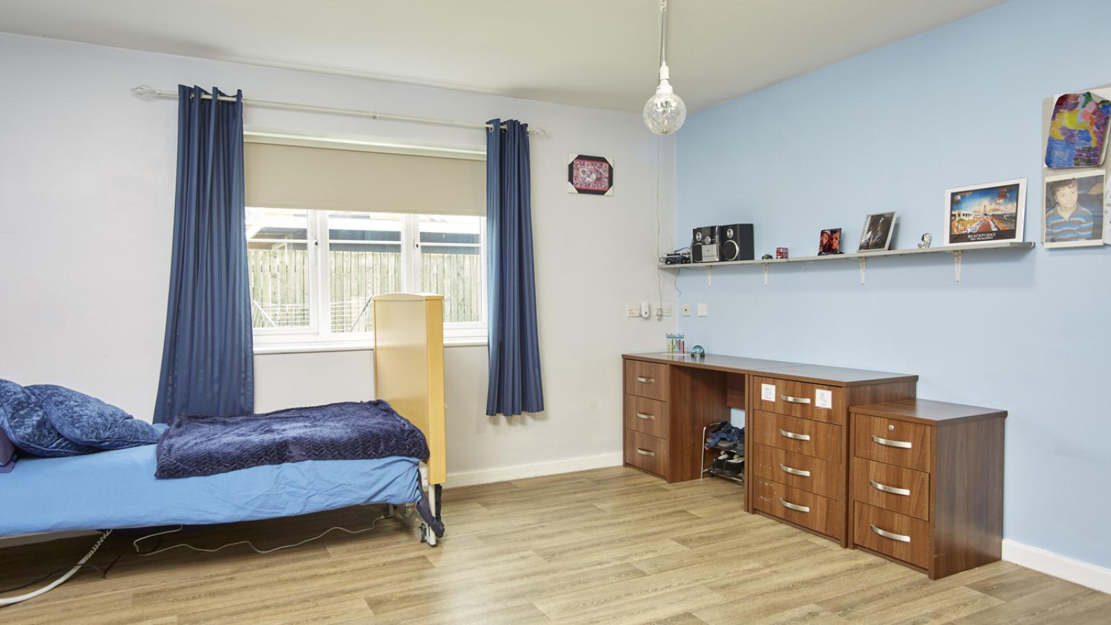 Large bedroom with bed and drawers, with personal decorations and photos