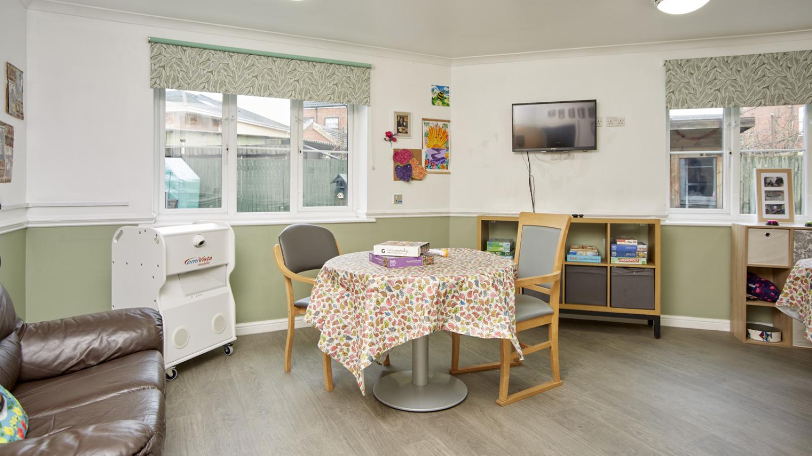 Room nicely decorated with green walls, set up as an activities room with games out on a table