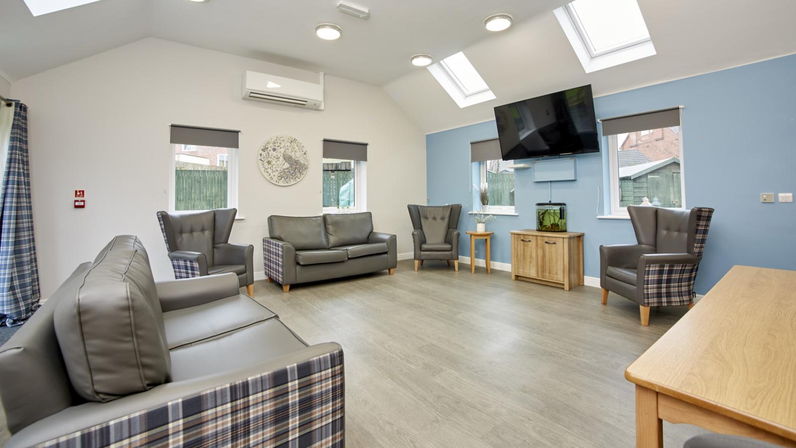 Nicely decorated lounge with bright sky lights, set up with chairs, sofas and a TV