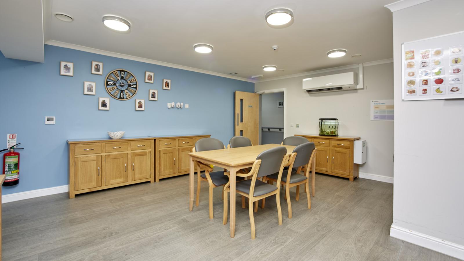 Dining room set up with table and chairs, with photos on the wall