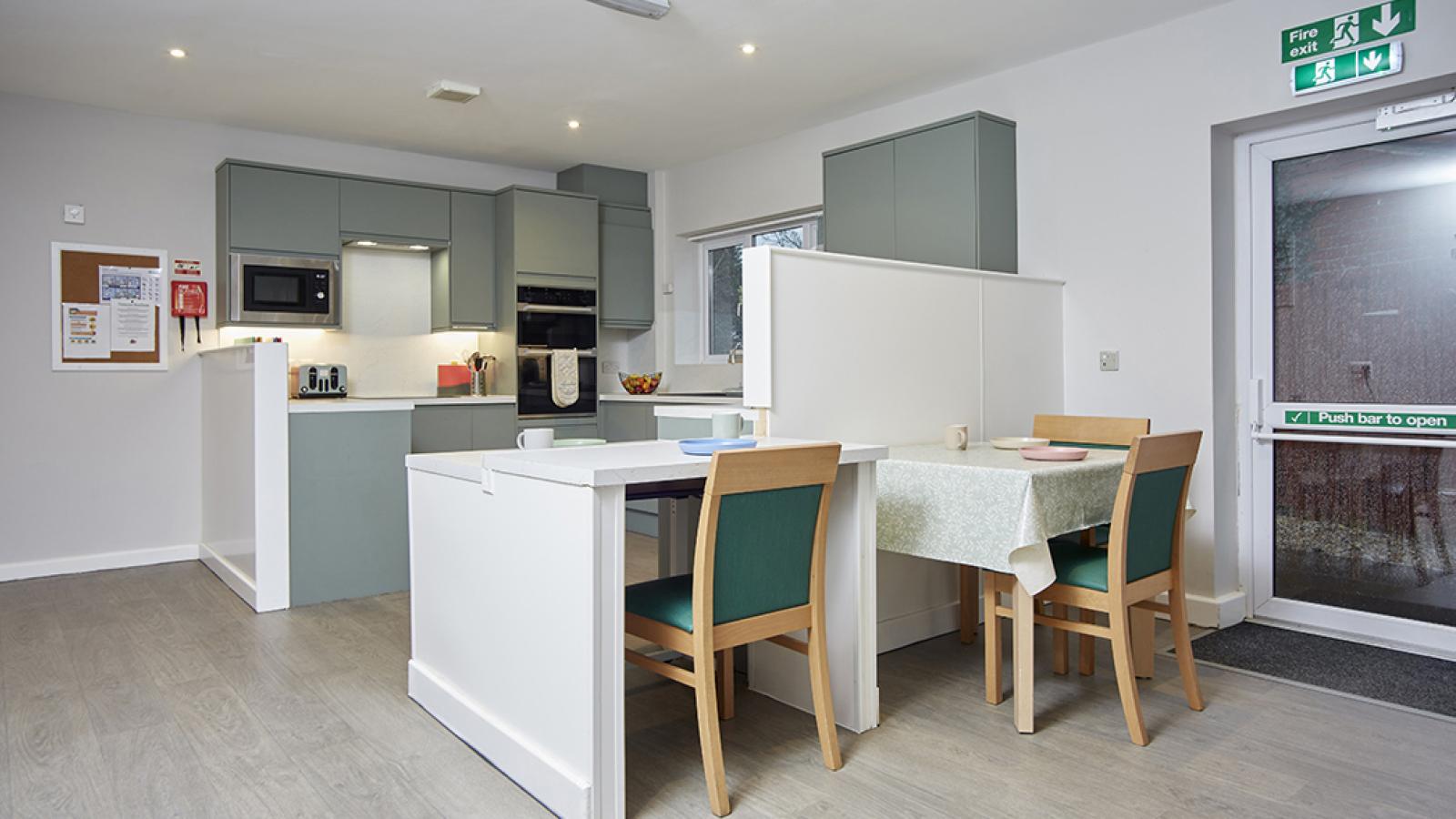 Kitchen with green cabinets, seating, and oven top