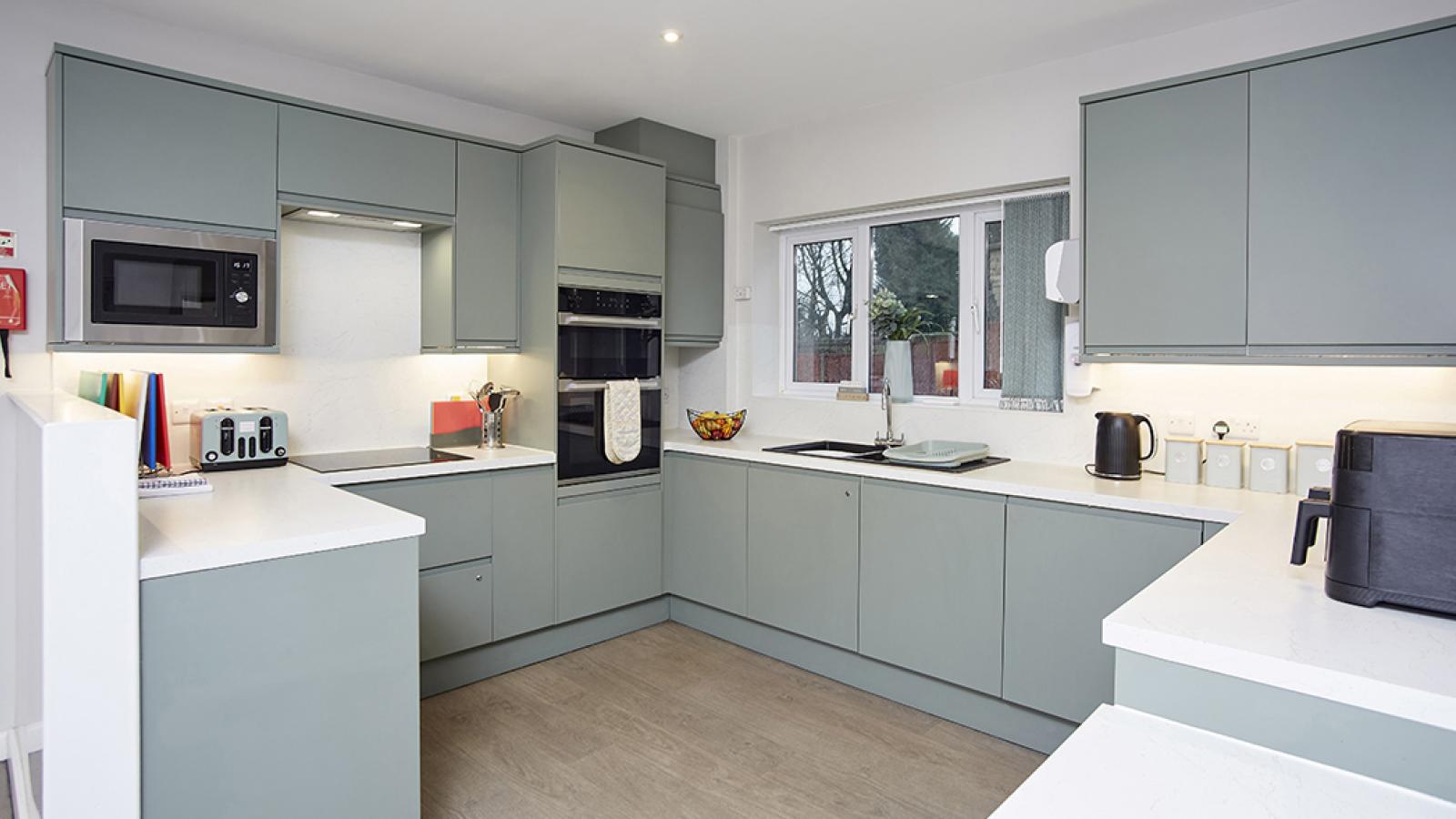 Kitchen with green cabinets, and built in oven and microwave
