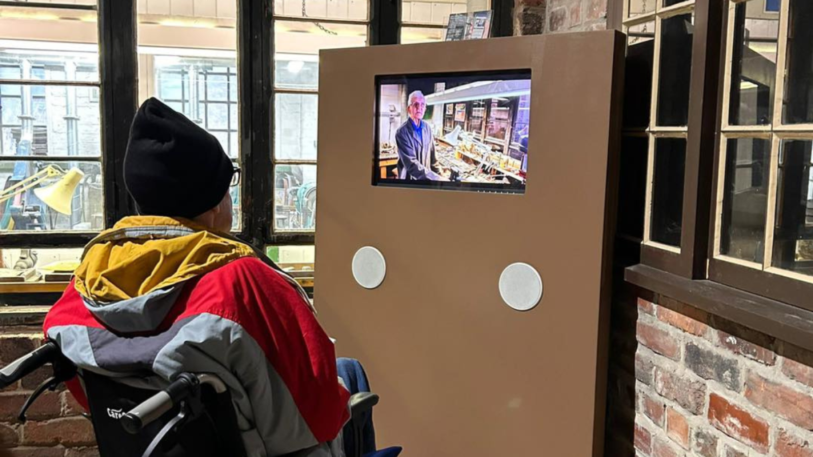 An man in a wheelchair observing a television screen, focused on the content being shown