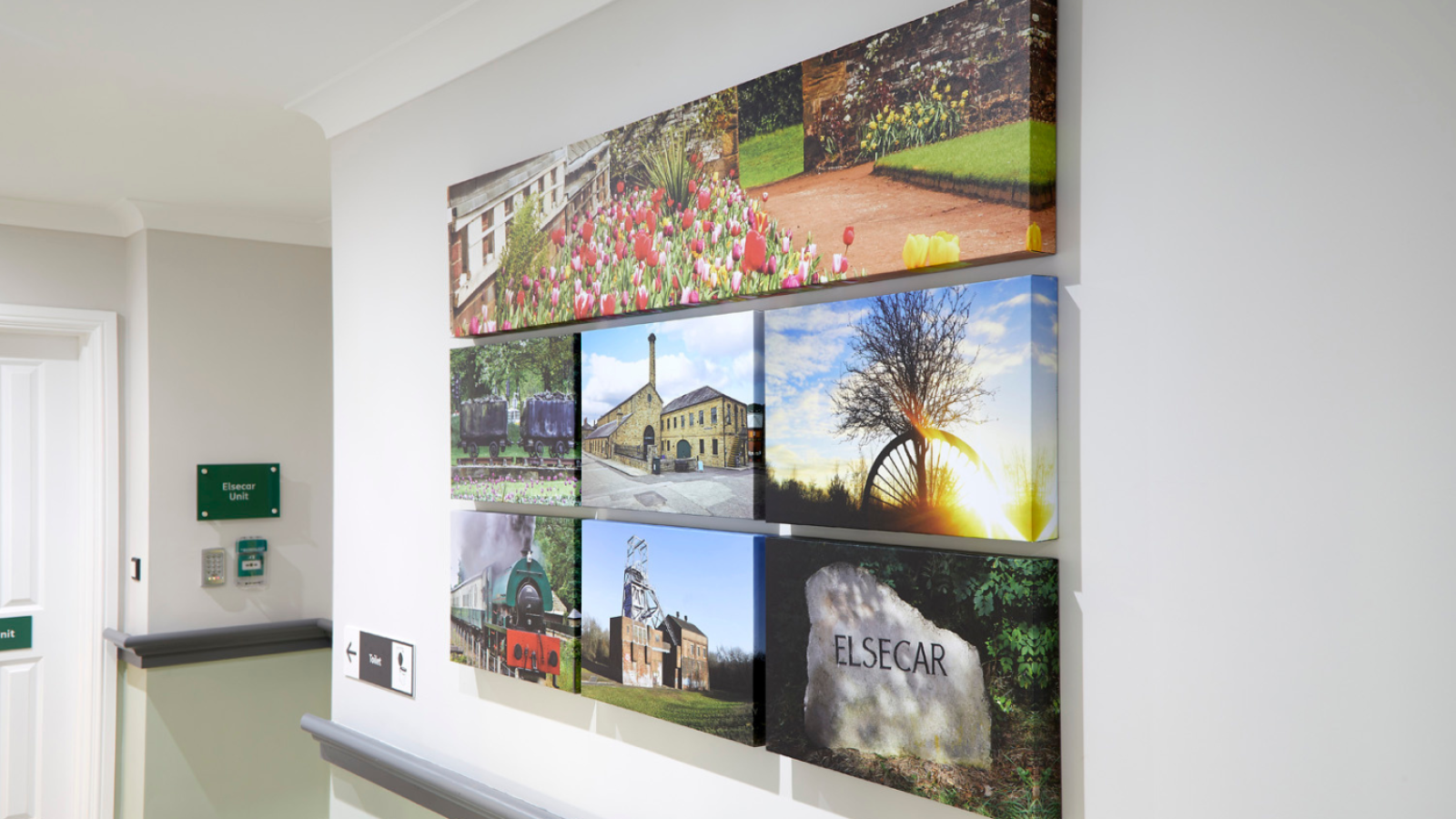 A hallway displays a collage of seven landscape photos featuring colorful tulips, historic buildings, a sunset, and a rock with "Elsecar" engraved.