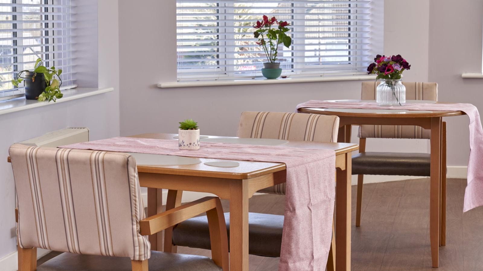 Dining room with pink walls, big windows, and two tables set up