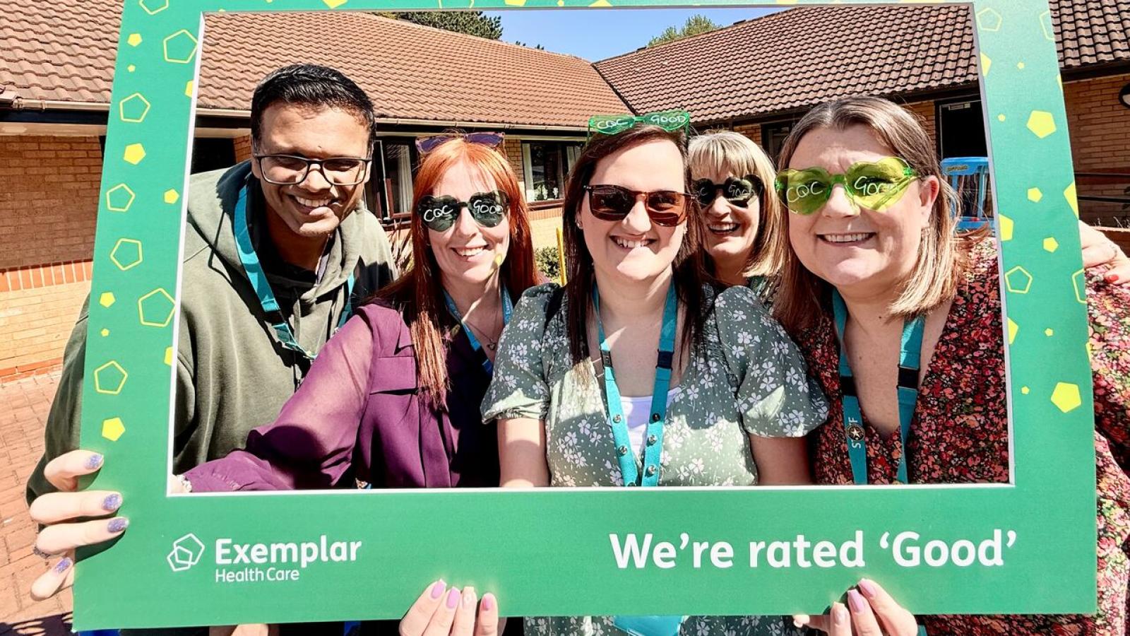 Group of five people smiling, celebrating with a green frame that says "Exemplar Health Care" and "We're rated 'Good'." Sunny outdoor setting.