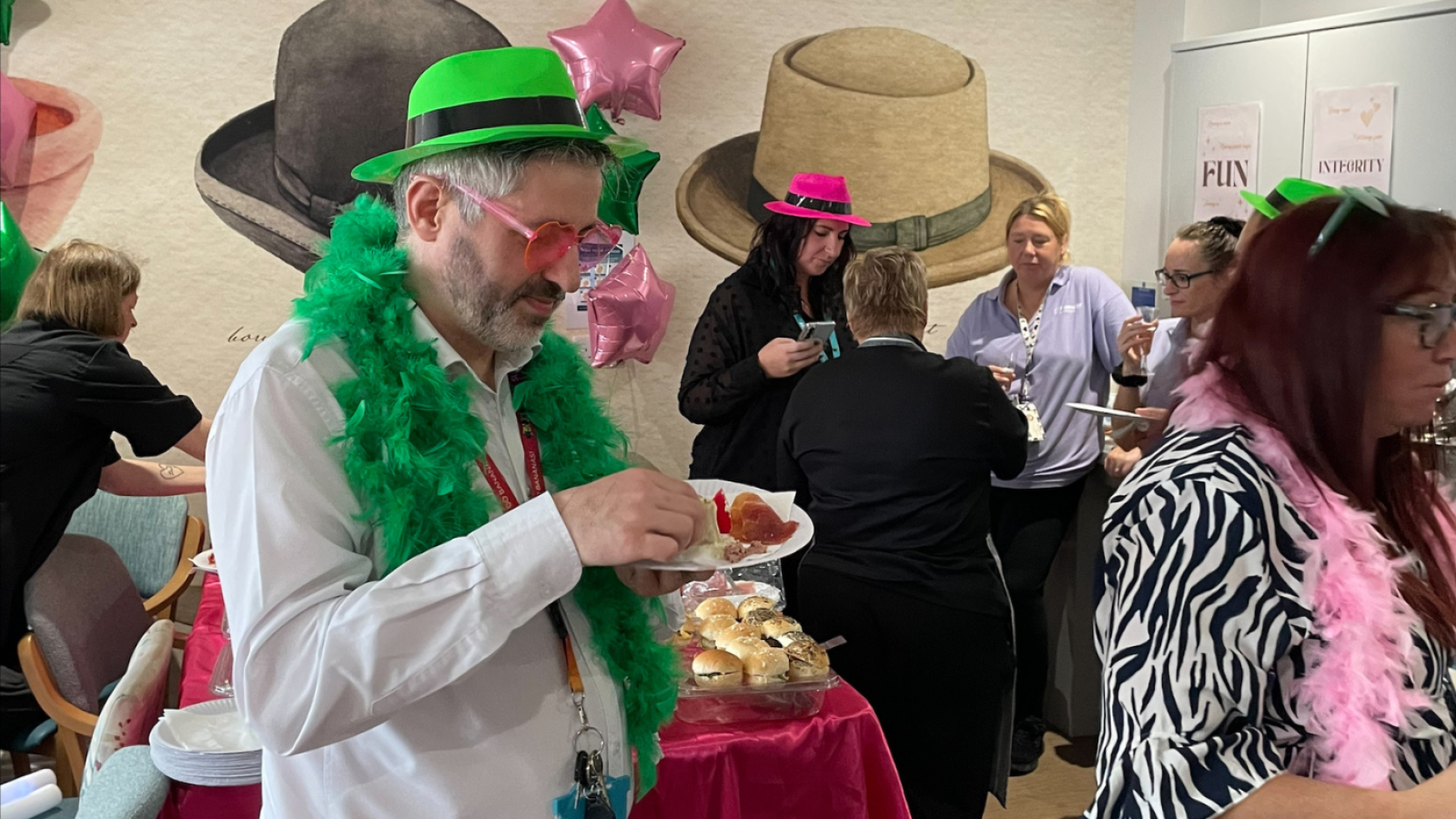 Partygoers adorned with green hats and feathers, enjoying a lively celebration together.