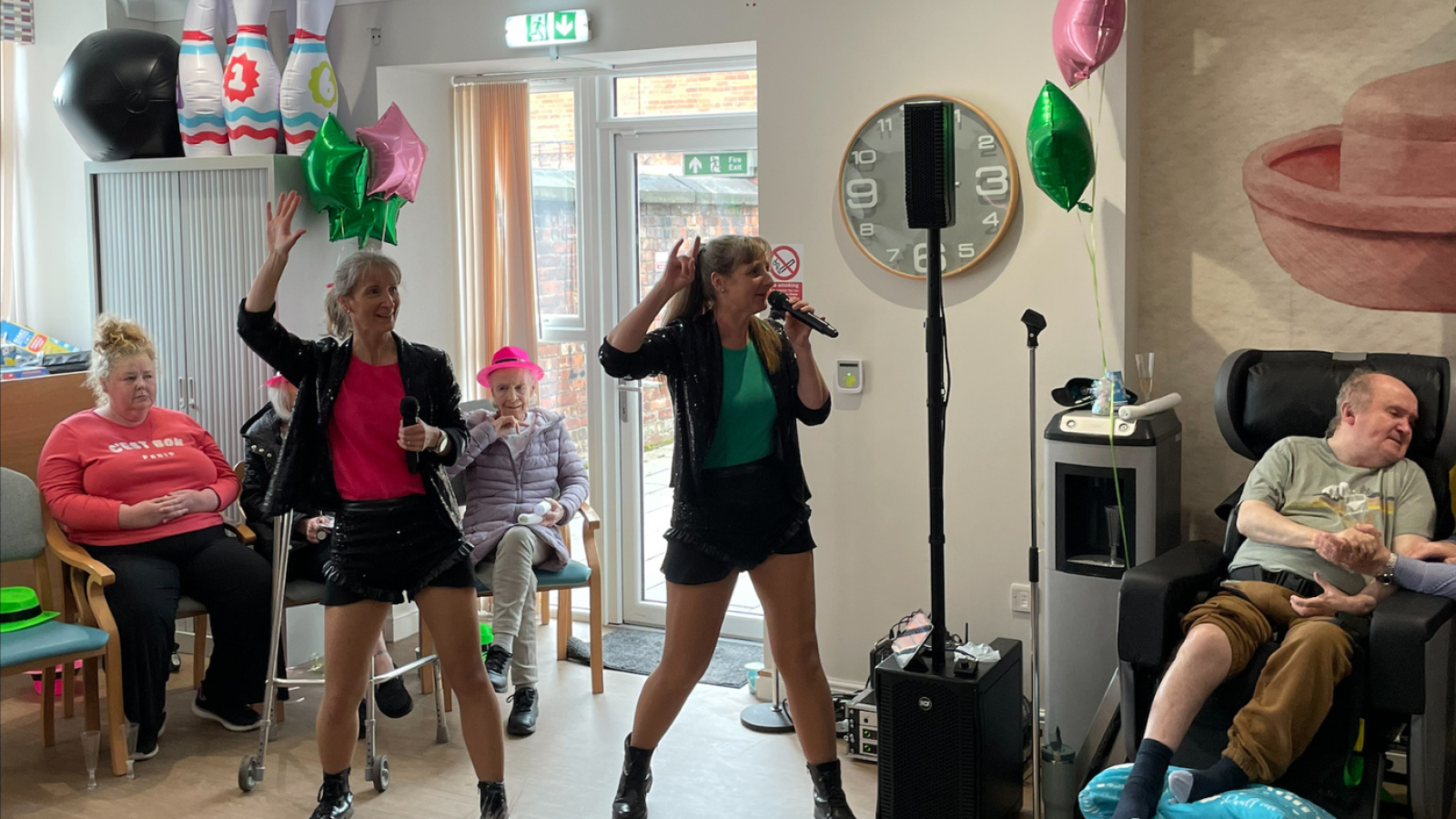 A group of people celebrating in a room filled with colorful balloons, creating a festive atmosphere.