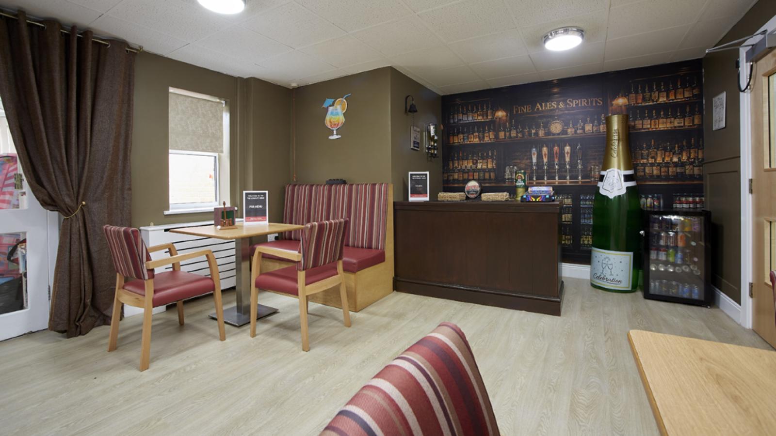 Cozy pub interior with striped seating, a table, and a bar. A large bottle decorates the corner, enhancing the ale-themed ambiance