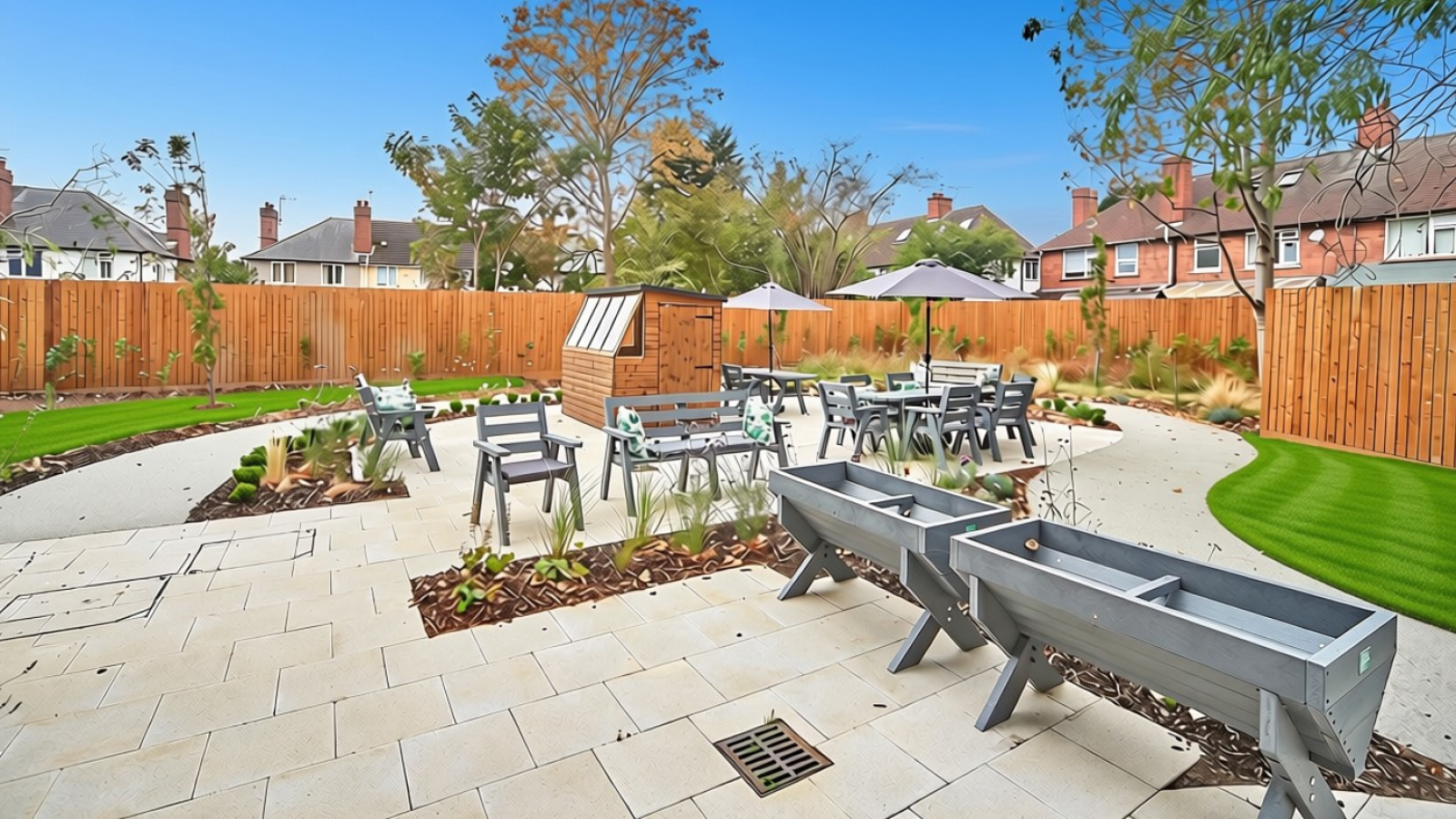 Modern landscaped courtyard with raised planters, outdoor tables and chairs, paved patio, lawn, wooden fence, and blue sky.